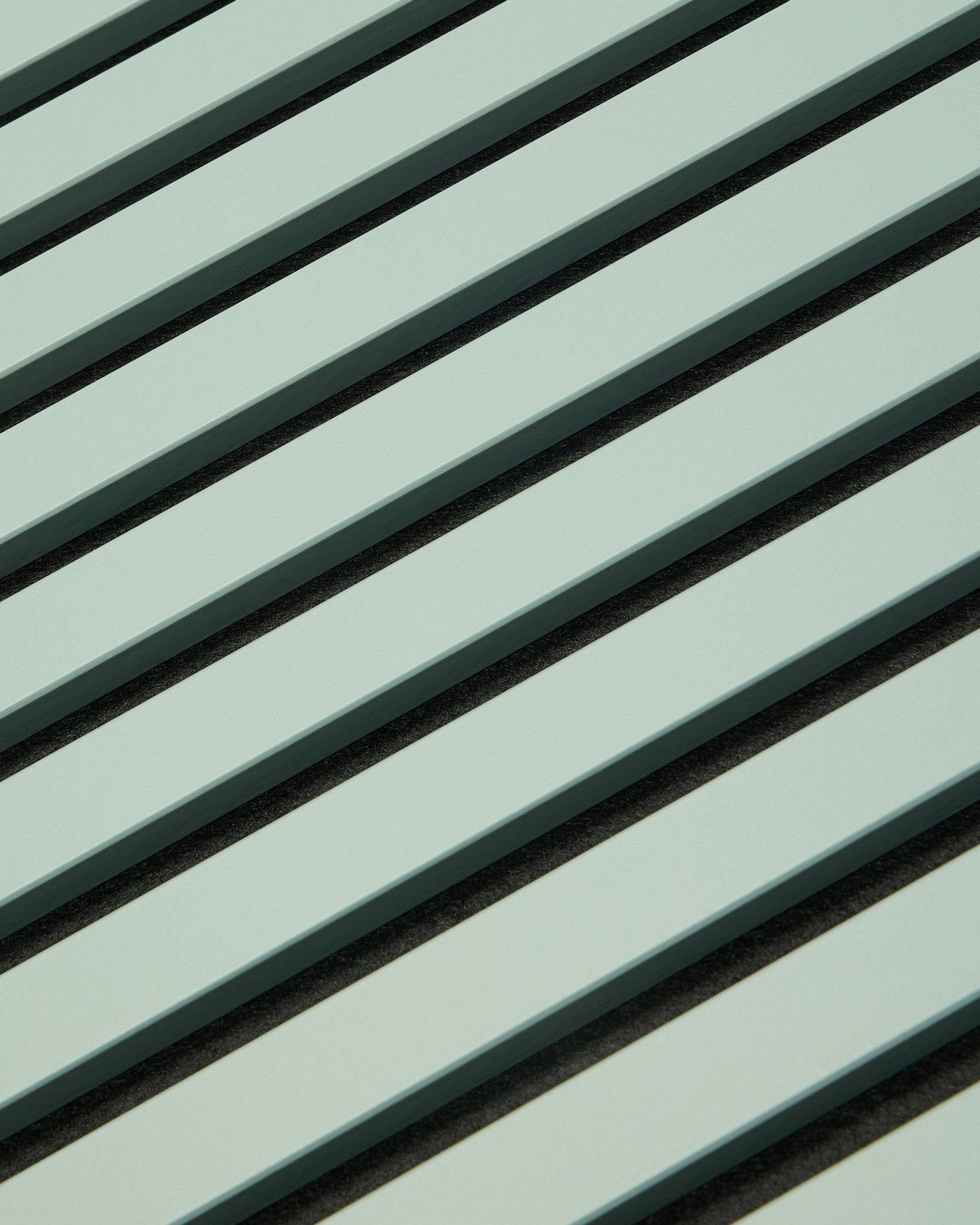 Hue | Akupanel / Cloud fra WoodUpp viser lysegrønne akustikpaneler i træ med vertical lameller og mørke mellemrum, som danner et geometrisk mønster til lydabsorption.